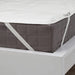 Gray quilted mattress cover on a white bed frame with a visible brand label.