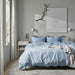 Neatly made bed with IKEA ÄNGSLILJA blue-grey duvet and pillows, fine stitching detail