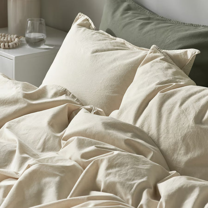 Neatly made bed with IKEA ÄNGSLILJA off-white cotton duvet cover and pillowcases