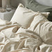 Neatly made bed with IKEA ÄNGSLILJA off-white cotton duvet cover and pillowcases