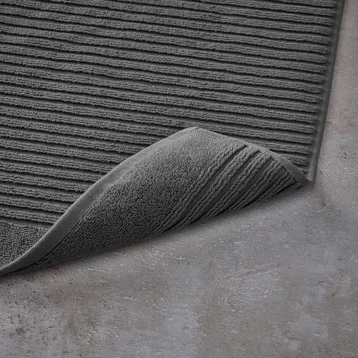IKEA ALSTERN dark grey bath mat and matching towel displayed on concrete floor bathroom setting