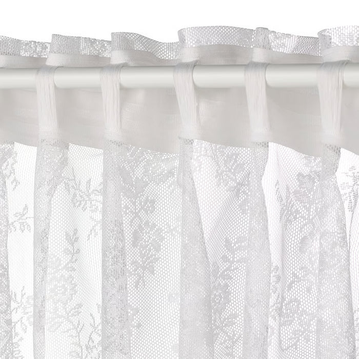 Close-up of IKEA ALVINE SPETS white curtain with delicate floral lace pattern and curved edges