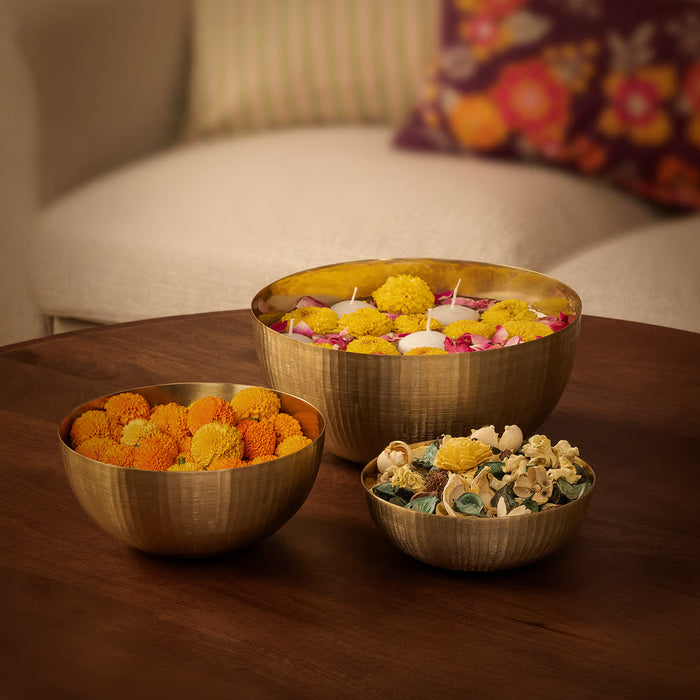 IKEA AROMATISK gold bowls styled with flowers and candles on wooden table
