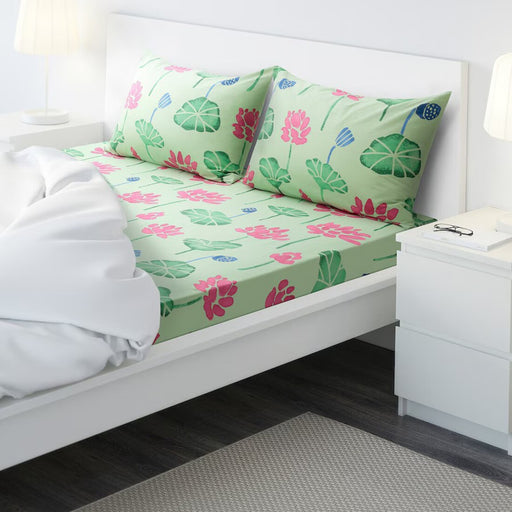 AROMATISK flat sheet and pillowcases set in green/pink, displayed on a bed with a vibrant floral design-00588986