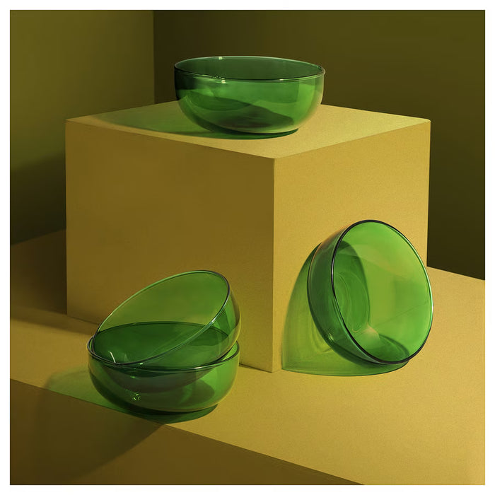 Two IKEA AROMATISK green glass bowls displayed on beige pedestal showing organic shape and polished finish