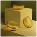 Three IKEA AROMATISK yellow glass bowls displayed on beige stand and table surface