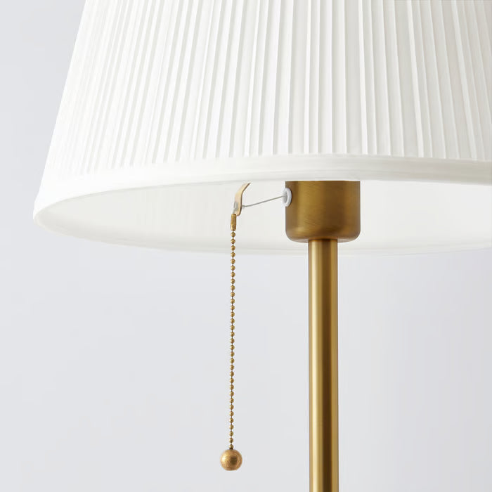  Close-up of IKEA ÅRSTID white pleated fabric shade with gold pull switch chain detail