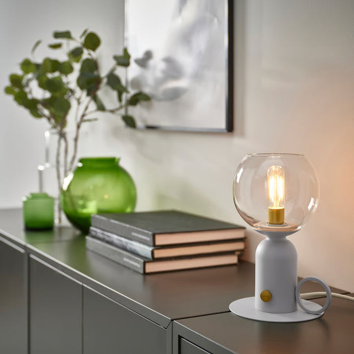 Scandinavian-designed IKEA ÅSKMULLER 24 cm tall table lamp in soft grey, combining metal construction with a textile shade for cozy ambient light.