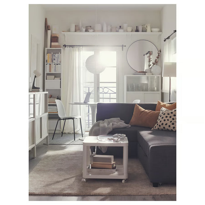 Modern living room with a gray sectional sofa, white coffee table, and bookshelf.