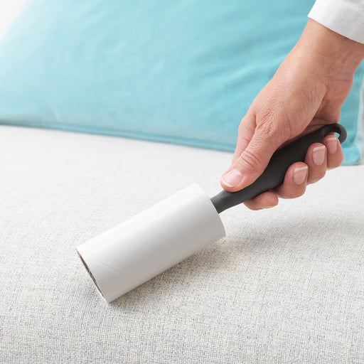 Person using IKEA BÄSTIS lint roller to remove lint from fabric clothing
