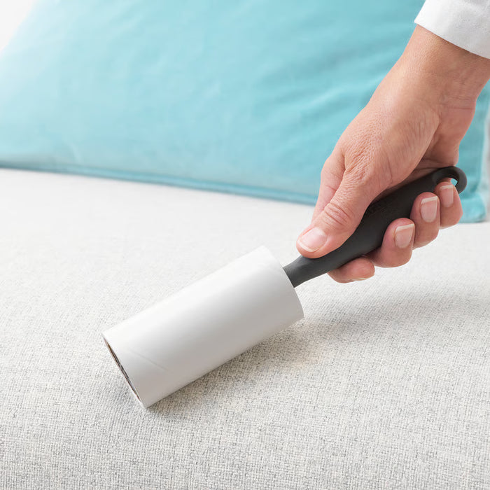 Person using IKEA BÄSTIS lint roller to remove lint from fabric clothing