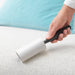 Person using IKEA BÄSTIS lint roller to remove lint from fabric clothing