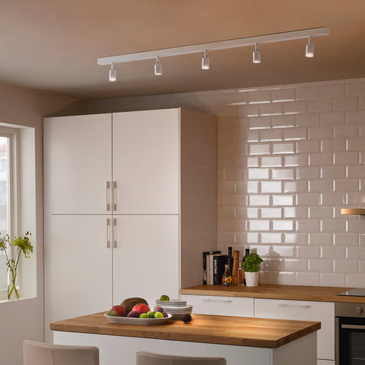 IKEA BÄVE 5-spot LED track light white installed in modern kitchen illuminating cabinet and wooden island