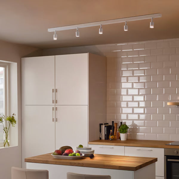 IKEA BÄVE 5-spot LED track light white installed in modern kitchen illuminating cabinet and wooden island