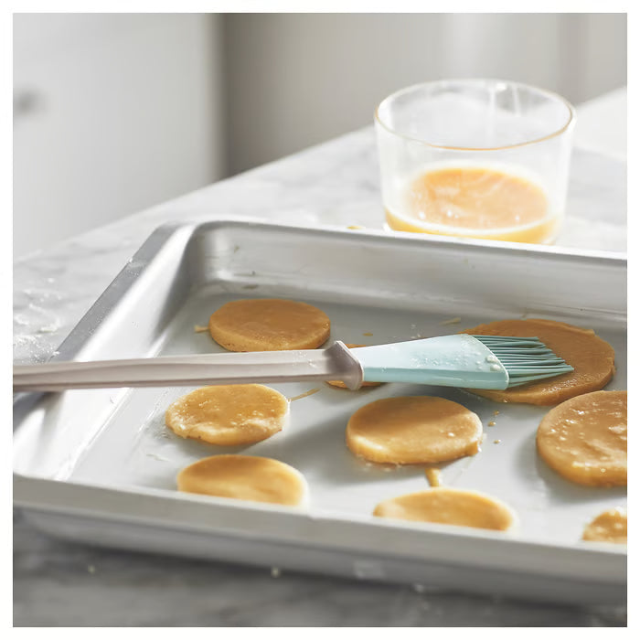 IKEA BAKGLAD blue silicone brush being used to glaze freshly baked muffins