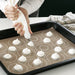 Person piping pastry dough onto IKEA BAKTRADITION baking mat using circular guides for even spacing