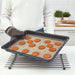 Person lifting baking tray with evenly baked cookies on IKEA BAKTRADITION mat over a cooling rack