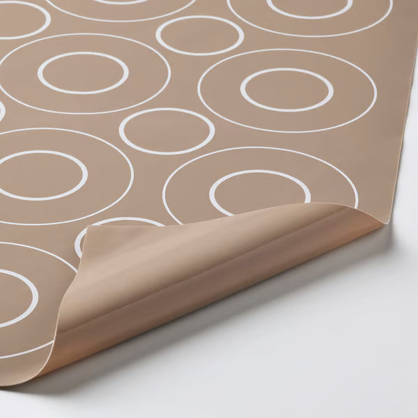 Close-up of IKEA BAKTRADITION beige silicone mat showing flexible texture and embossed circular pattern