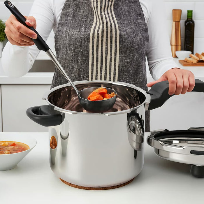 Person serving cooked vegetables from IKEA BANDGURAMI pressure cooker with a ladle