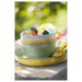 Stack of colorful ceramic bowls on a table with a blurred green outdoor background
