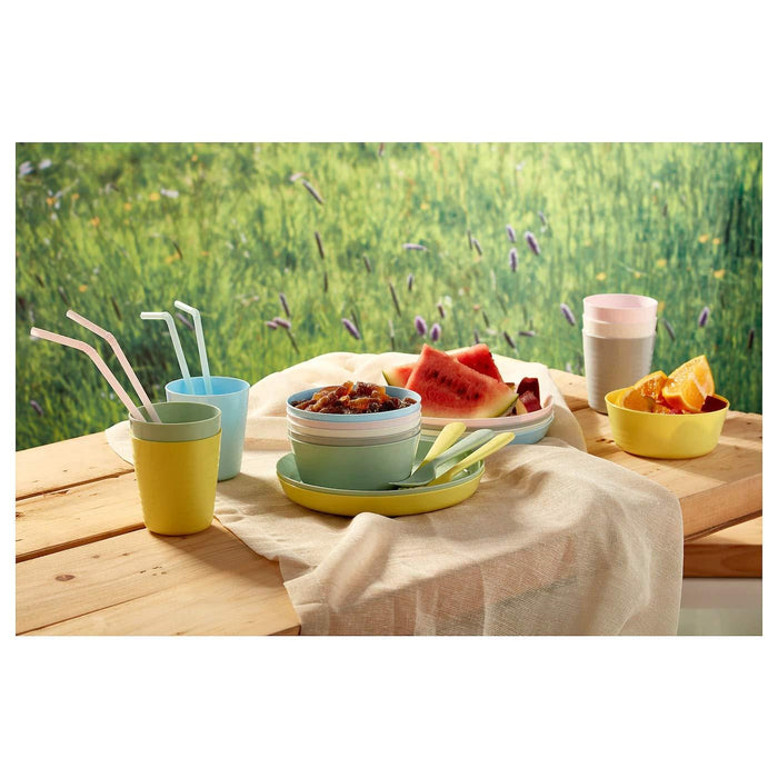 Outdoor setting with colorful tableware on a wooden table against a grassy background