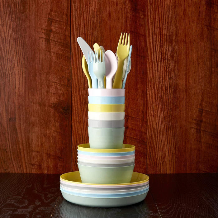 Stacked colorful ceramic plates with cutlery on a wooden surface