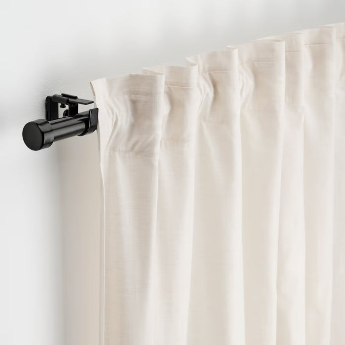 White curtains hanging from IKEA BEKRÄFTA black curtain rod with wall brackets and connector visible