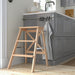 IKEA BEKVÄM beech step stool folded next to kitchen cabinets showing slim profile