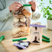 : Person sealing a bread bag with green IKEA BEVARA clips beside coffee bag on wooden table