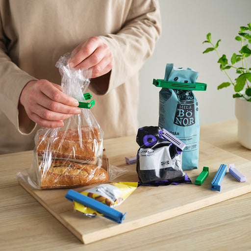 IKEA BEVARA sealing clips in mixed colours used to seal a bread bag on a kitchen table with food items