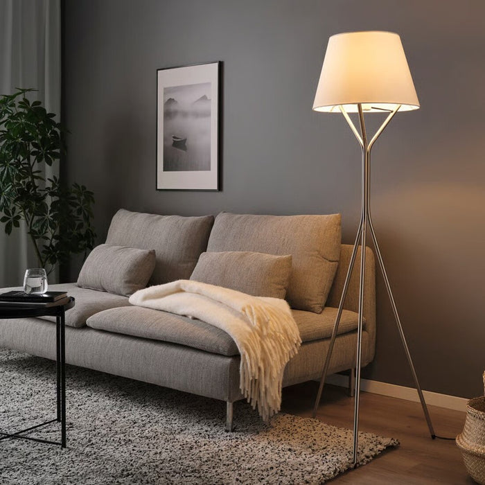 A sleek nickel-plated floor lamp with a curved arm and a white fabric shade, providing adjustable lighting for living rooms or workspaces.
