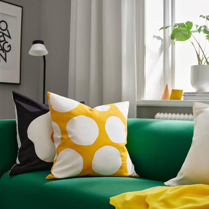 IKEA BLÅMUNKAR yellow polka dot cushion cover on green sofa in modern living room