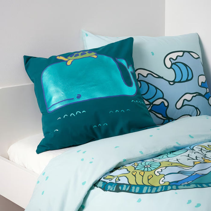 Two IKEA BLÅVINGAD cushions with whale and turtle designs styled on a bed