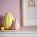 IKEA BLODBJÖRK white and yellow striped vase standing tall among decorative table items