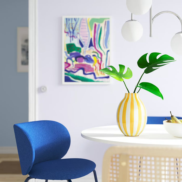 IKEA BLODBJÖRK striped vase holding green leaves on small table beside blue chair