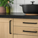 IKEA BORGHAMN black handles fitted on wooden kitchen cabinet doors with dark countertop and herbs