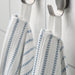 Close-up of folded IKEA BROKGINST white bath towels showing waffle side and terry side detail