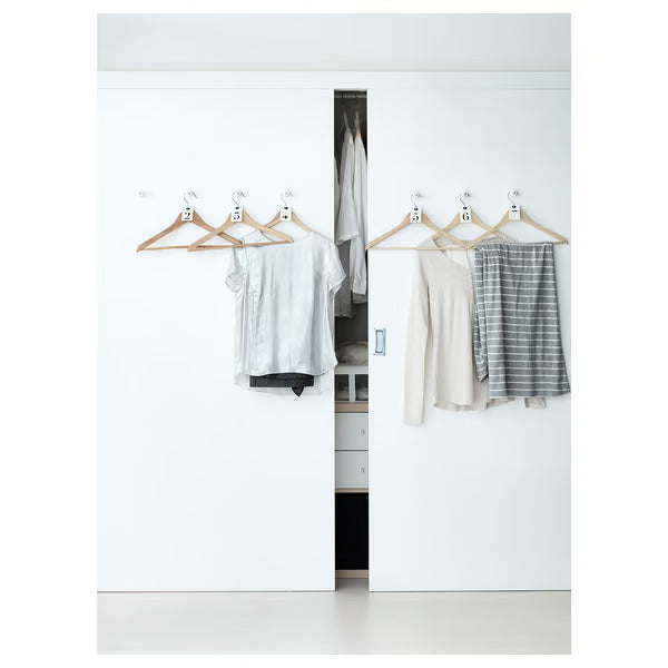 IKEA BUMERANG natural wood hangers in white wardrobe with blouse, sweater and striped skirt