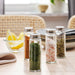 Person using IKEA CITRONHAJ spice jar to season stir-fried vegetables in copper skillet