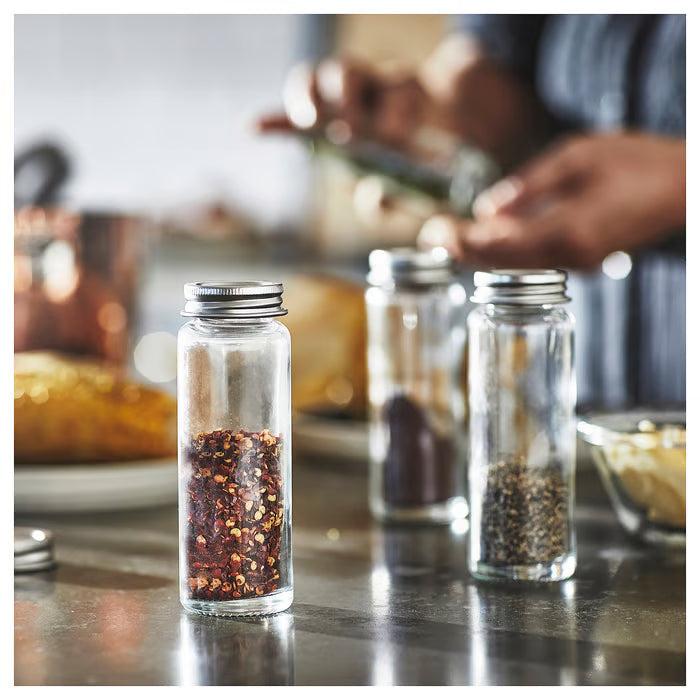 IKEA CITRONHAJ glass spice jars on kitchen counter next to wooden cutting board with chopped herbs