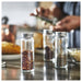 IKEA CITRONHAJ glass spice jars on kitchen counter next to wooden cutting board with chopped herbs