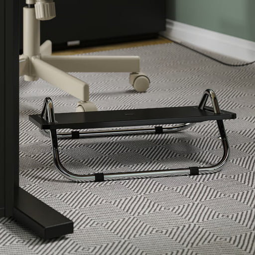 IKEA DAGOTTO black foot rest placed on patterned carpet under desk chrome frame side angle