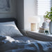 IKEA DEJSA lamp glowing softly on white shelf beside books and plant