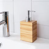 IKEA DRAGAN bamboo soap dispenser with metallic pump on bathroom sink close-up warm setting