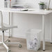  White IKEA DRÖNJÖNS wastebasket placed beside a desk showing size in a home office