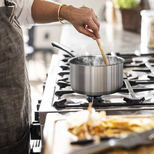 Person stirring IKEA DVÄRGKRÄFTA stainless steel saucepan on gas stove with steam rising