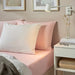 Bedroom styled with IKEA DVALA light pink cotton sheet pillows and blanket with white side table