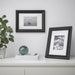 IKEA EDSBRUK black frames styled on white shelf with boat and butterfly photos, books and plant in background