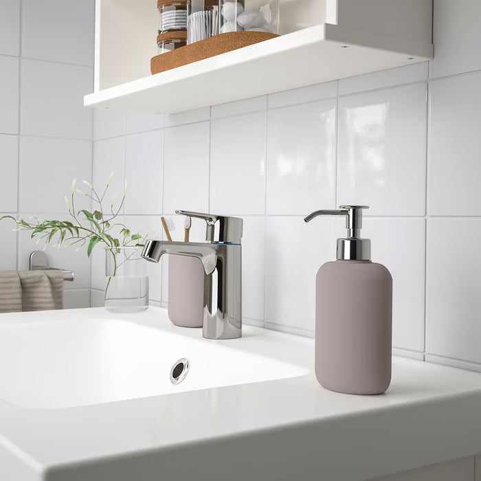 IKEA EKOLN beige soap dispenser on white bathroom counter with modern silver tap, lifestyle setting