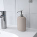 KEA EKOLN beige soap dispenser placed beside bathroom sink, styled with coordinating EKOLN accessories